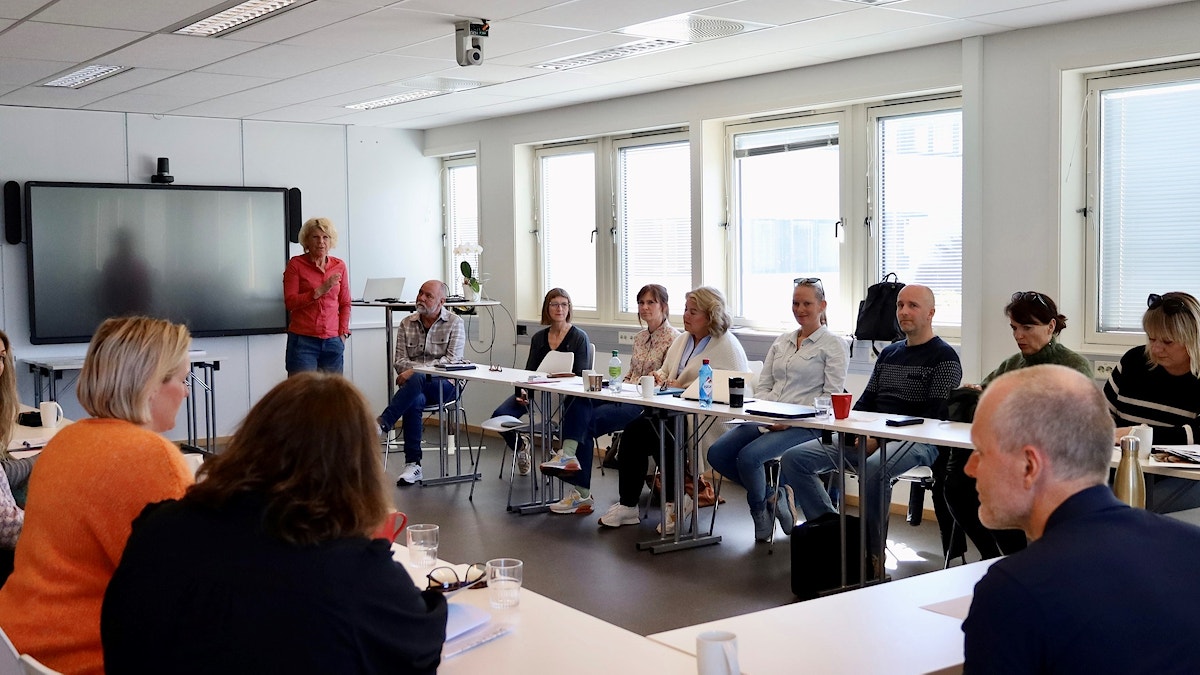 Bildet viser en kvinnelig foreleser i et klasserom hvor pultene står i en U-formasjon.