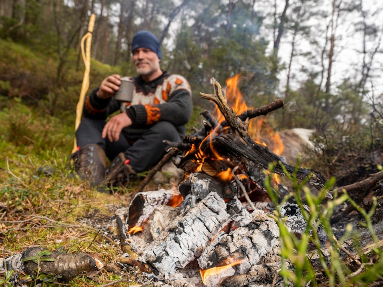 Bilde av Are Lerstein som sitter ved bålet og drikker kakao.