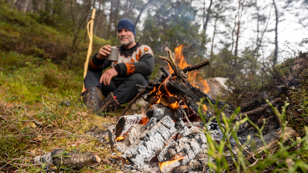 Bilde av Are Lerstein som sitter ved bålet og drikker kakao.