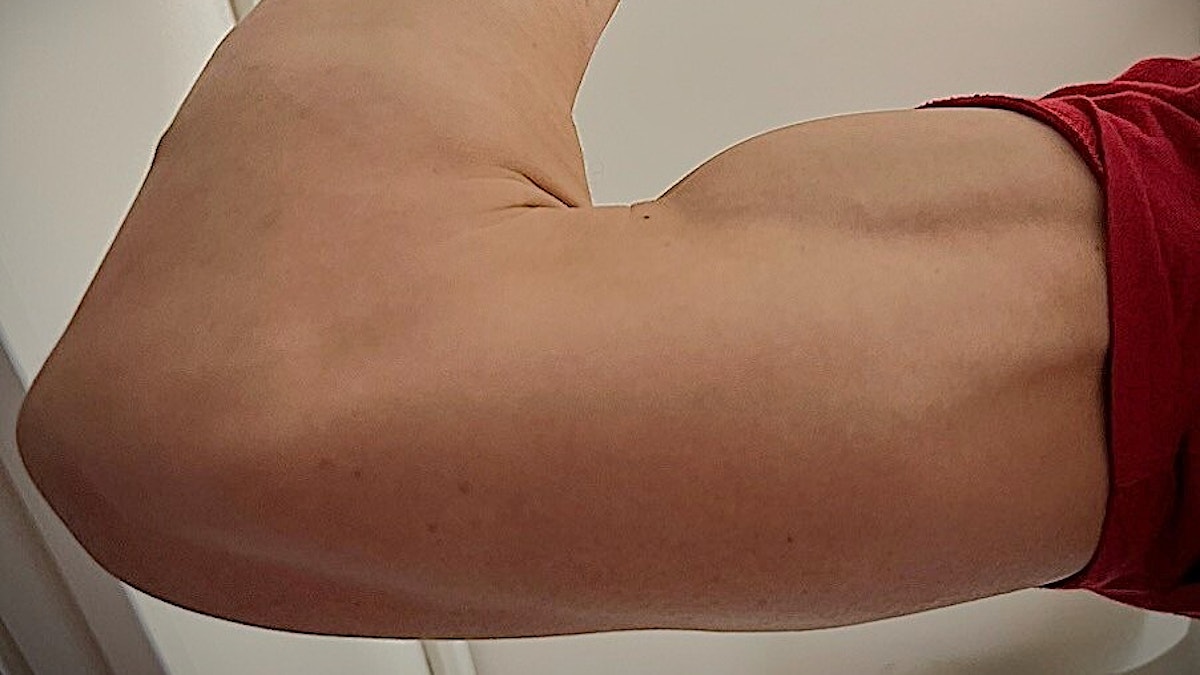 Bicep strammes, flik av rød t-skjorte synes. Illustrasjonsfoto.