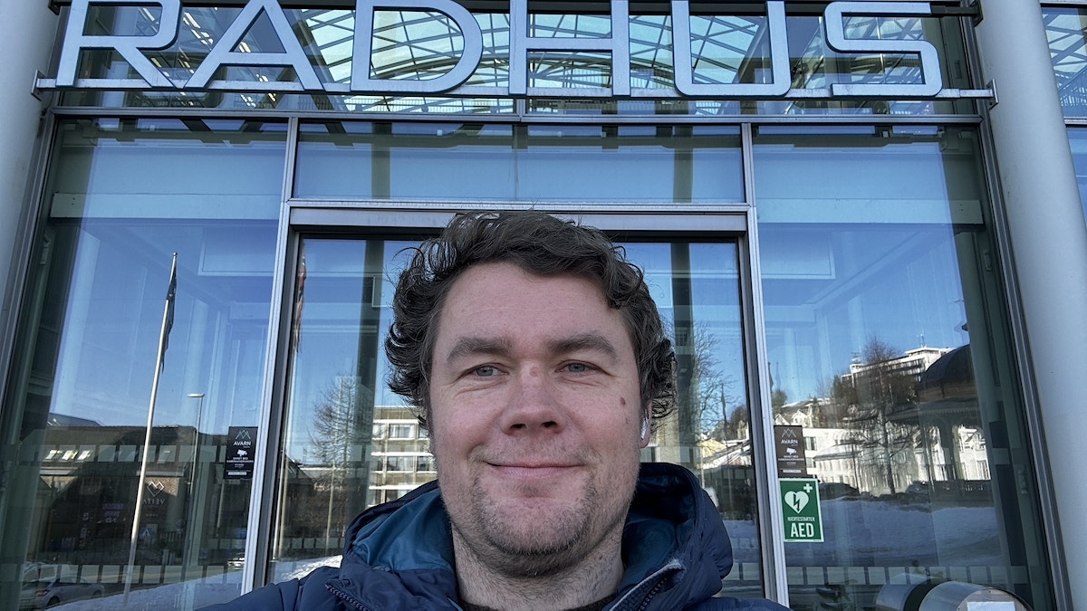 Stian Falck Eidissen står foran rådhuset i Tromsø. Han smiler fornøyd.
