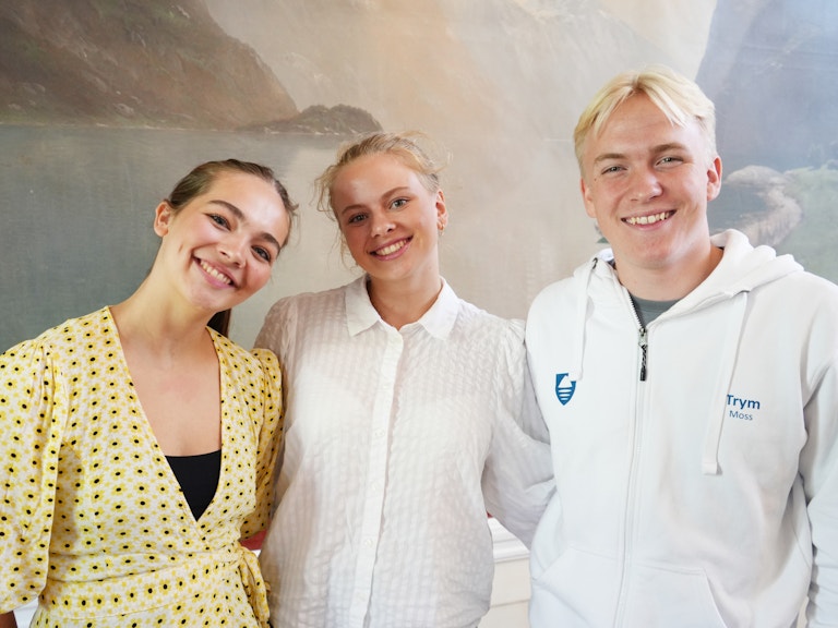 Tre ungdommer fra Vestfold og Telemark står inne på Gamle rådhus i Arendal. De er blide og fornøyde.