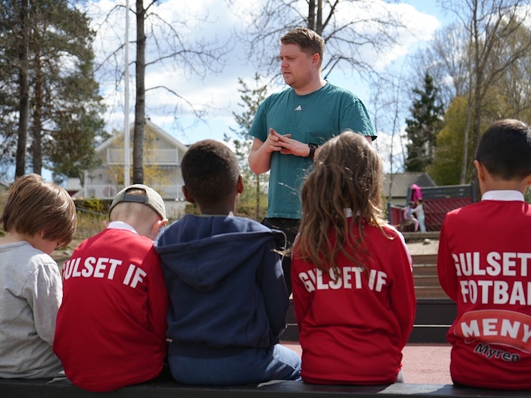 Mats står foran en gruppe barn kledd i de røde draktene til Gulset IF.