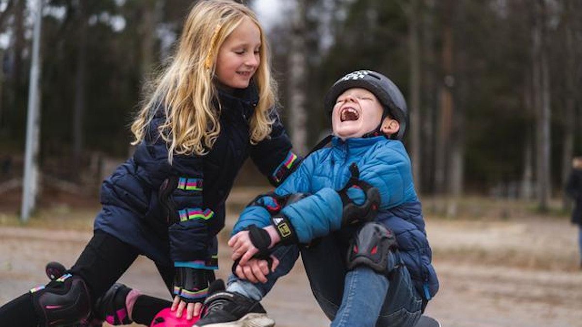 To barn leker sammen på en lekeplass. Det ene barnet sitter på et rullebrett og ler. (Foto: Jonas Ingstad)
