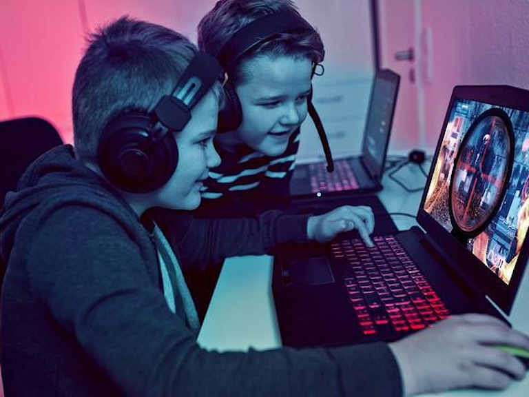 To barn sitter foran en PC og spiller skytespill.