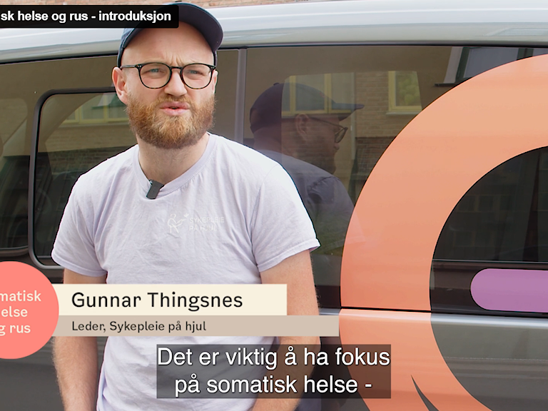 Gunnar Thingsnes fra Sykepleiere på hjul står foran en minibuss og forteller om det nye e-læringsprogrammet.