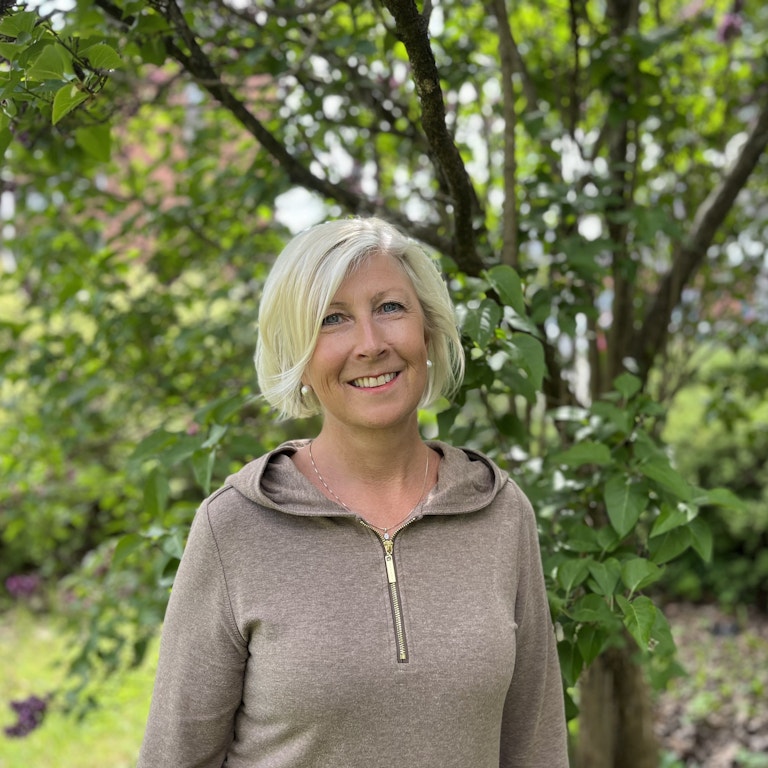 Portrett av Hilde Jeanette Loberg. Hun står utendørs og i en grønn hage.