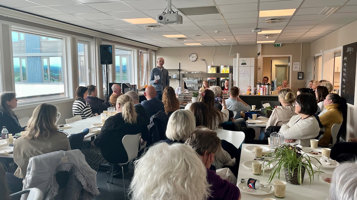Bilde tatt bakfra i en kantine full av folk. Kantinen er full, men vi ser bare bakhoder. Alle ser på Rogaland A-senters direktør Bjarte Grov som holder en tale.