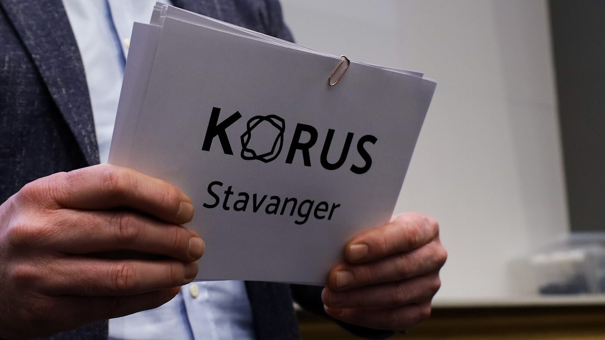 To hender holder en bunke med kort hvor det står skrevet «KORUS Stavanger»