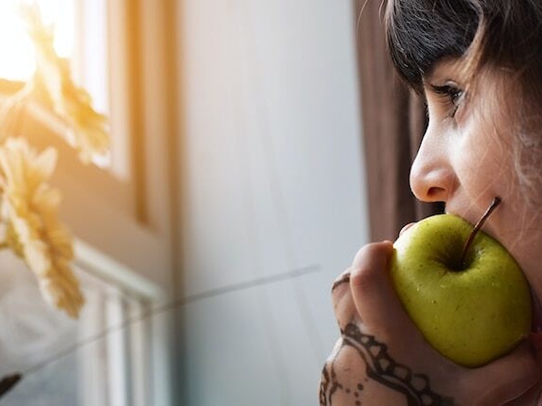 kvinne spiser eple mens hun ser ut av et vindu