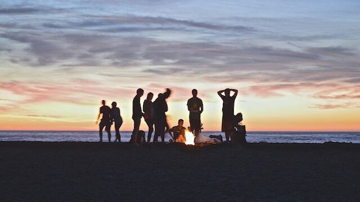 stor gjeng på strand i solnedgang
