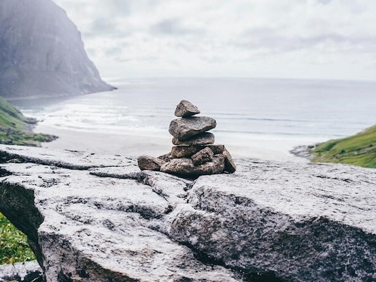Bilde av steiner oppå hverandre foran en strand i Nord-Norge.