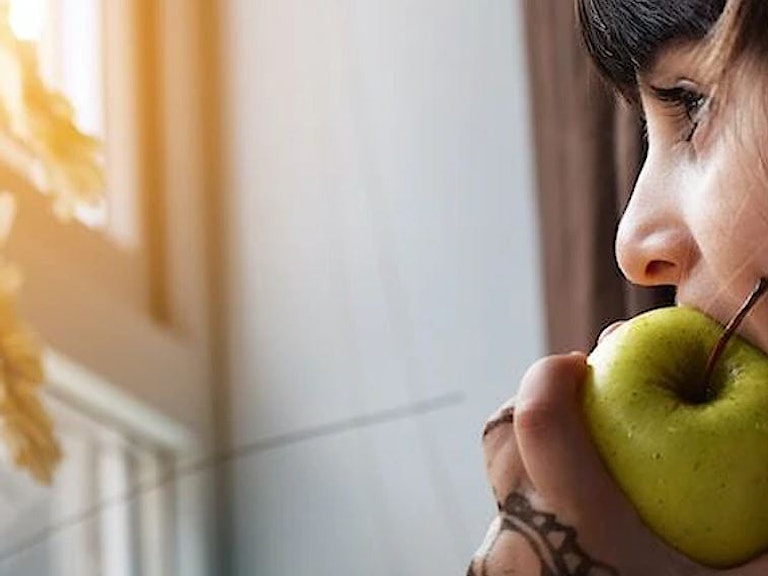 kvinne spiser eple og ser ut av vinduet